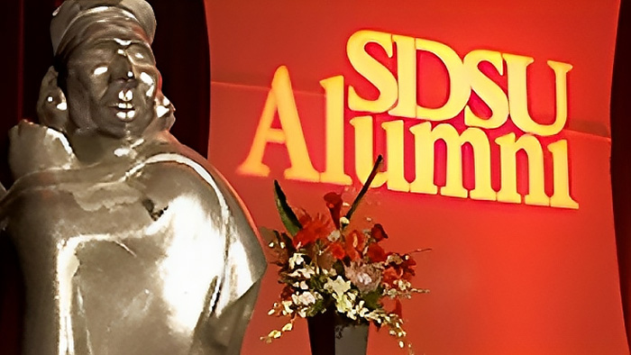 A large replica of the Monty Award statue on stage in front of a SDSU Alumni banner